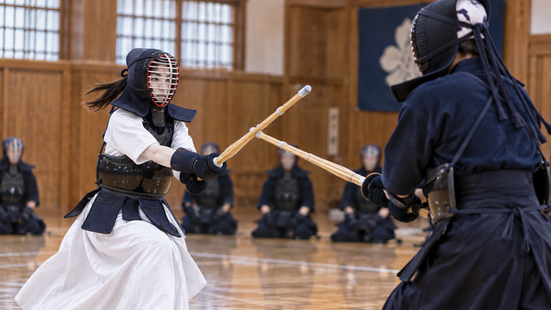 剣道場で女性剣士と男性剣士が向かい合って対戦する様子をイメージしたイラスト