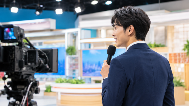 テレビスタジオでマイクを持つ若手男性アナウンサー