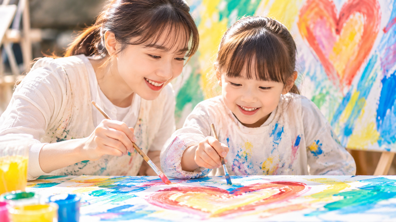 女性と女の子が一緒に絵を描くアートパフォーマンスのイメージ
