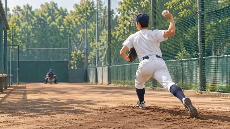 大学野球場のブルペンで投球練習をする右投手のイメージ